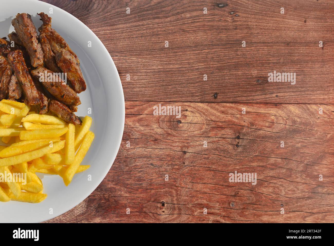 Gustosa bistecca a fette guarnita con patatine fritte. Sfondo di legno Foto Stock