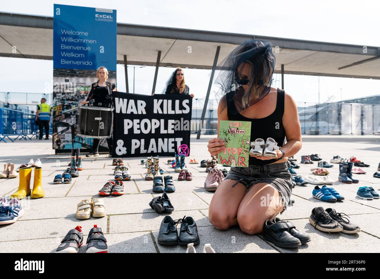 Londra, Regno Unito. 10 settembre 2023. Gli attivisti della ribellione dell'estinzione manifestano all'esterno dell'ingresso della mostra DSEI presso l'Excel Center di Londra. I manifestanti hanno messo scarpe per bambini davanti a uno striscione che diceva "la guerra uccide persone e pianeta". Crediti: Andrea Domeniconi/Alamy Live News Foto Stock