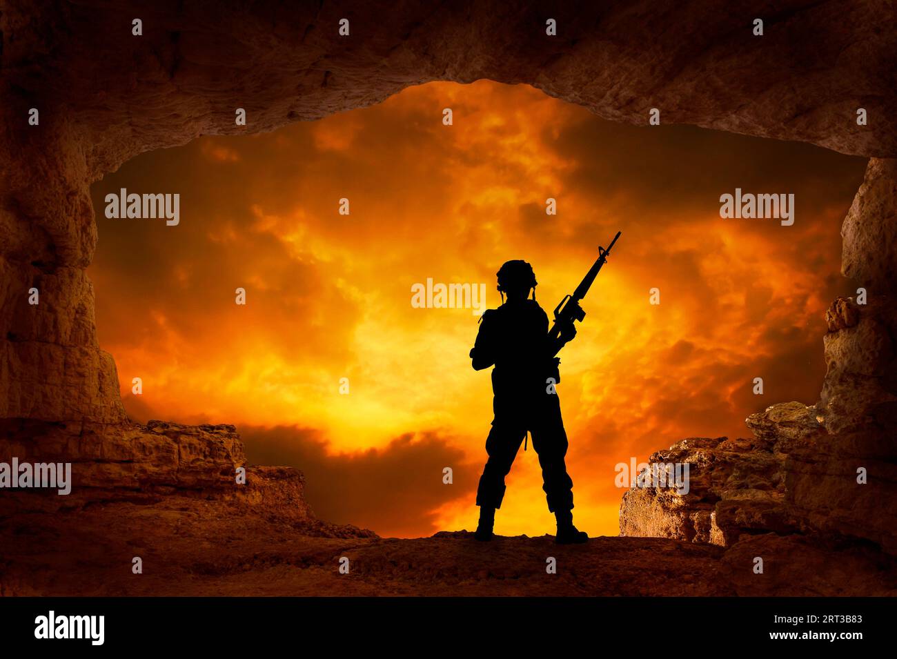 soldato con una pistola in silhouette al bordo di una caverna Foto Stock