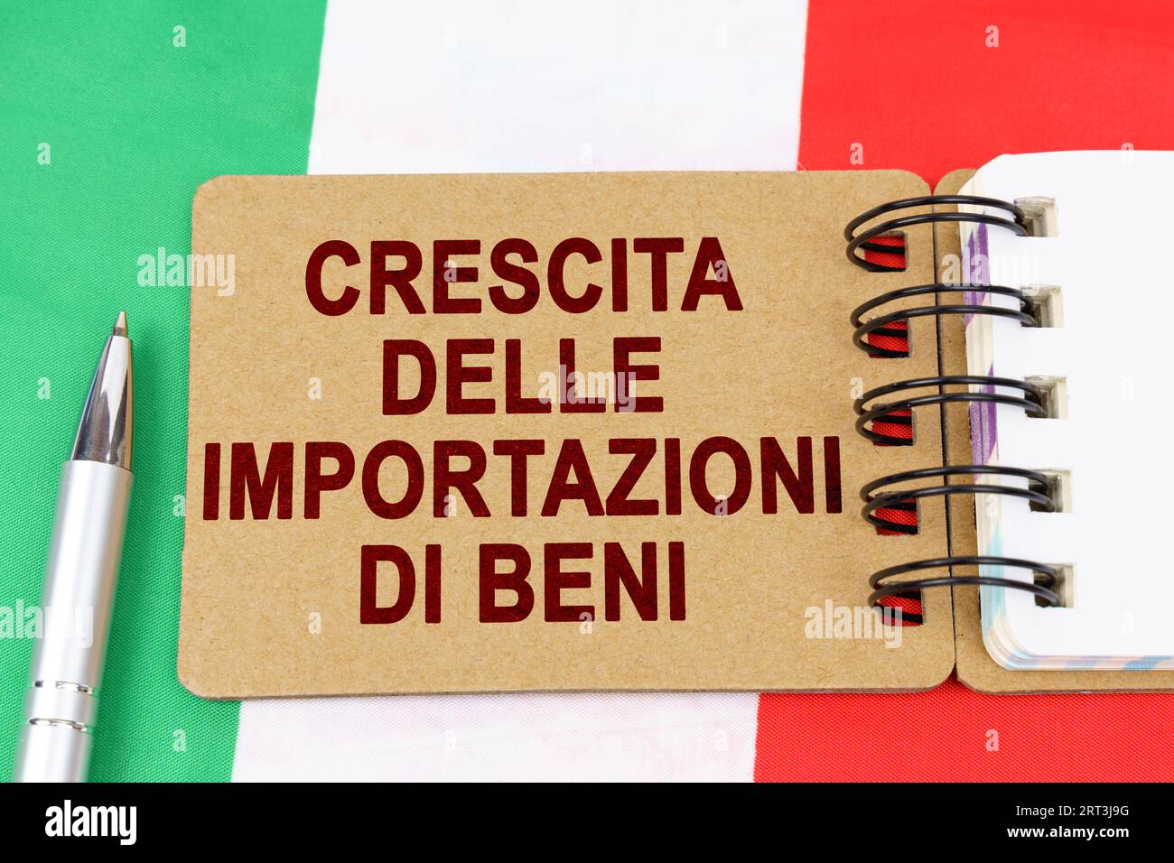 Economia e finanza. Sulla bandiera dell'Italia si trova una penna e un quaderno con l'iscrizione - crescita delle importazioni di beni. Testo in italiano. Foto Stock