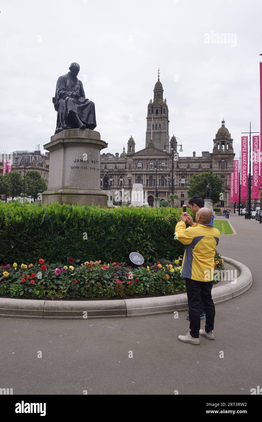 Glasgow, Scozia (Regno Unito): Un turista sta sta scattando una foto della statua di James Watt a George Square Foto Stock