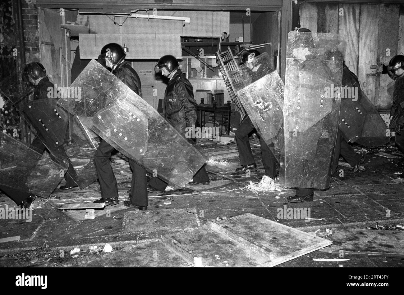 Toxteth Riots 1980S.. Gli edifici sono stati incendiati, la polizia con gli scudi che attraversano un edificio saccheggiato. Toxteth, Liverpool, Inghilterra Regno Unito luglio 1981 HOMER SYKES Foto Stock