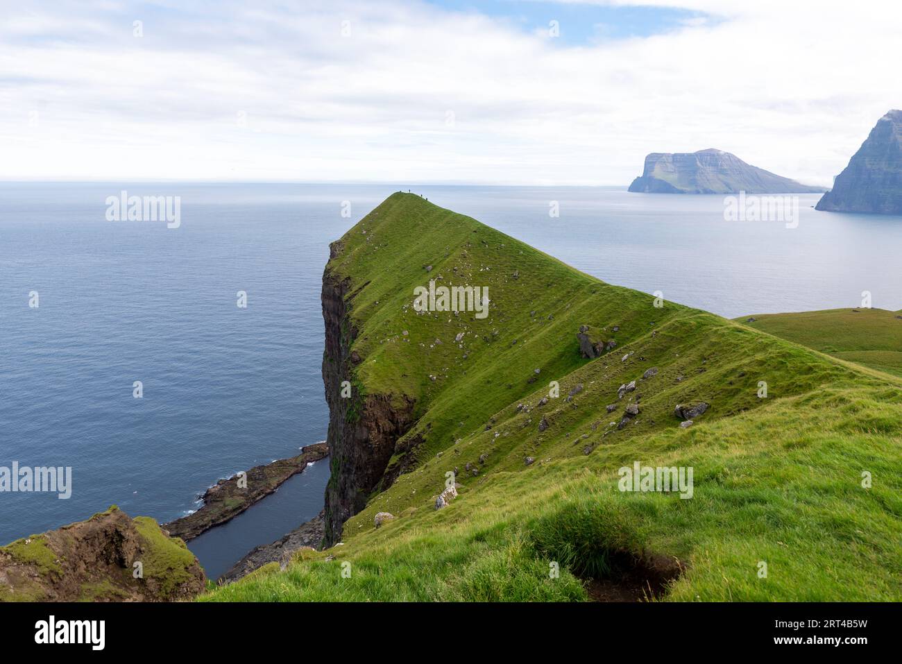 Cresta erbosa vicino al faro di Kallur, all'isola di Kalsoy e alle isole Faroe Foto Stock