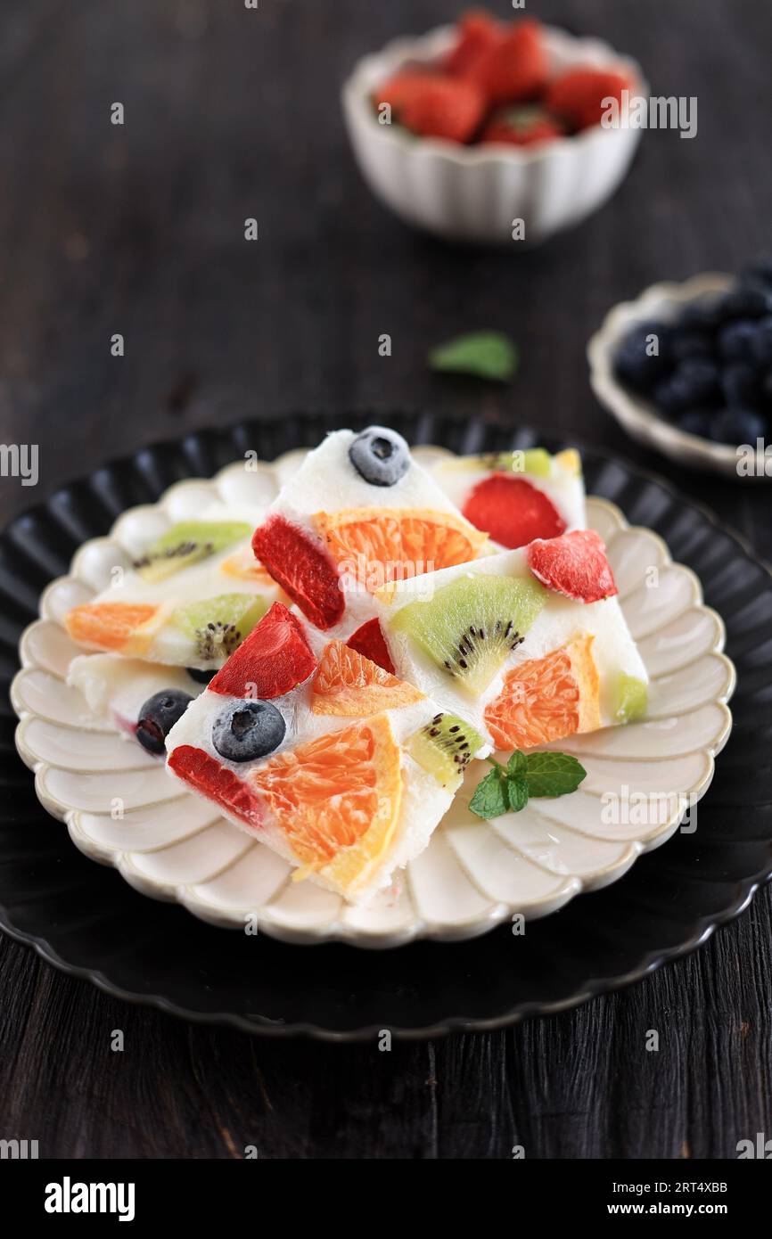 Bar di yogurt greco salutare con fragole, mirtilli, kiwi e arancia. Corteccia di yogurt surgelato su un tavolo di legno Foto Stock