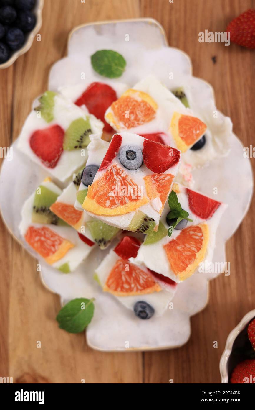 Top View Bar con corteccia ghiacciata di yogurt greco fatto in casa, frutta fresca, frutti di bosco, kiwi e arancia Foto Stock