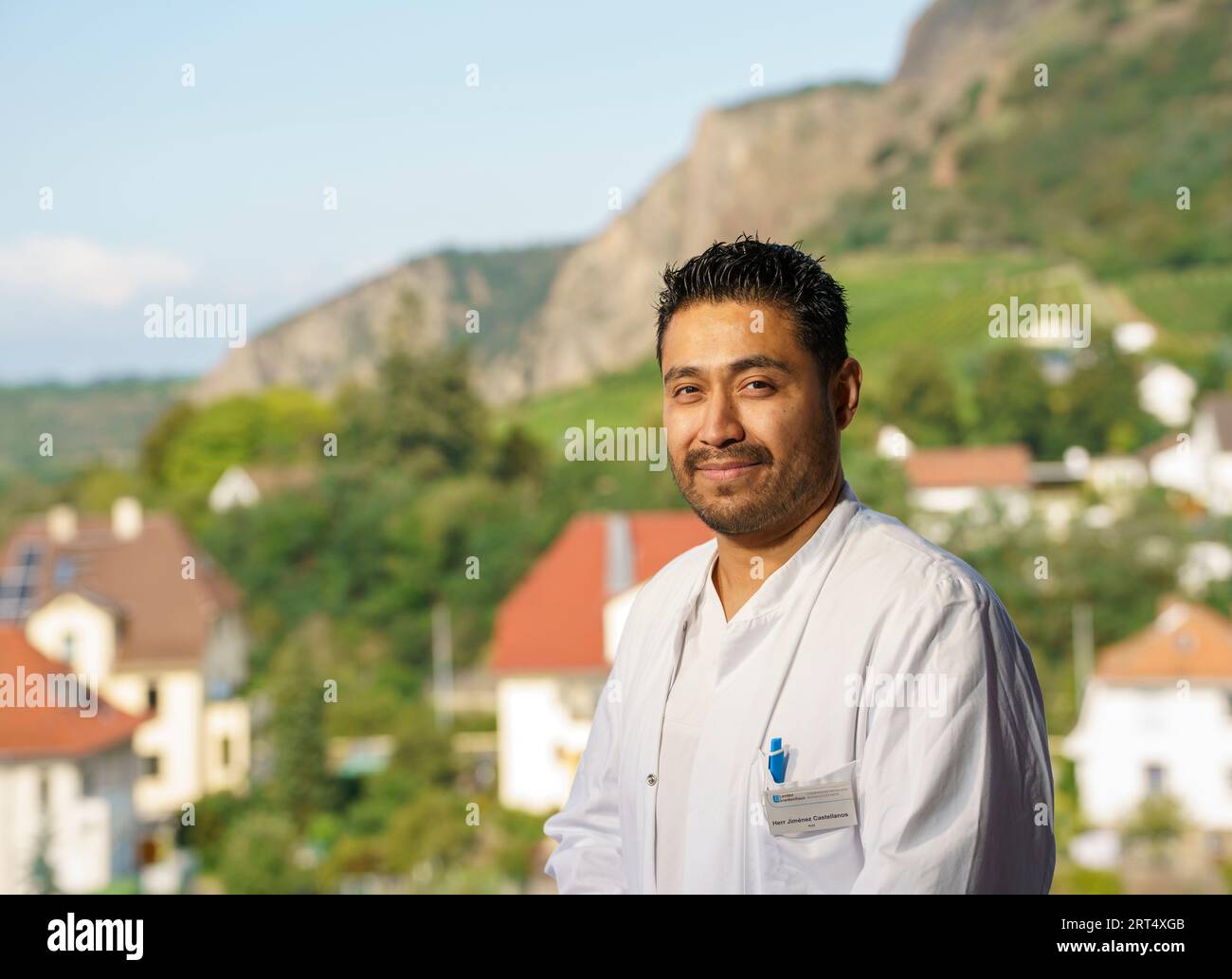 Bad Kreuznach, Germania. 30 agosto 2023. José Jiménez, medico geriatrico specialista clinica Rheinhessen-Nahe, si trova sulla terrazza sul tetto di fronte allo sfondo dei "Rotenfels", uno dei punti di riferimento di questa regione. Con il programma "Specialized!”, l'Agenzia federale per l'occupazione, si deve contrastare la carenza di lavoratori qualificati in campo medico. La Geriatric Specialized Clinic Rheinhessen-Nahe impiega, tra gli altri, un medico di città del Messico dal 2022. (Al dpa "Medici e infermieri dall'estero per alleviare la carenza di lavoratori qualificati") credito: Andreas Arnold/dp/dpa/Alamy Live News Foto Stock