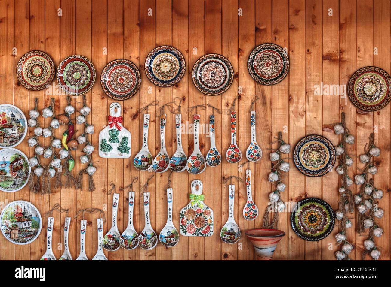 Negozio turistico in Bulgaria con piatti di ceramica e ceramica, cucchiai, aglio, su una parete di legno di pino Foto Stock