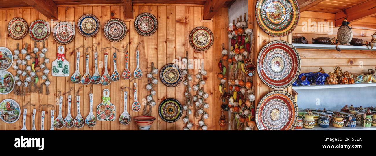 Negozio turistico in Bulgaria con piatti di ceramica e ceramica, cucchiai, aglio, su una parete di legno di pino Foto Stock