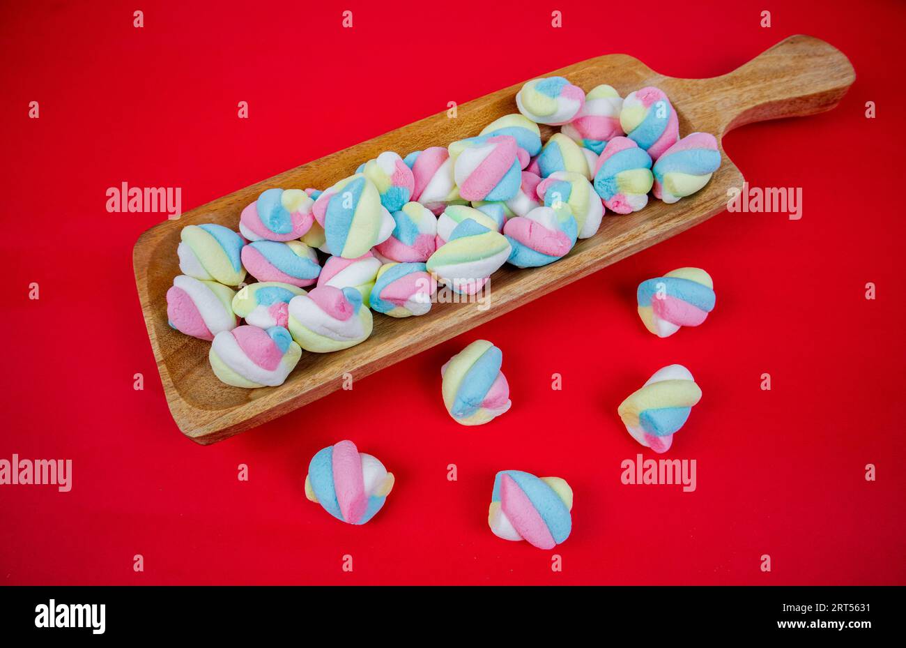 caramelle di marshmallow in piatto di legno su fondo rosso Foto Stock