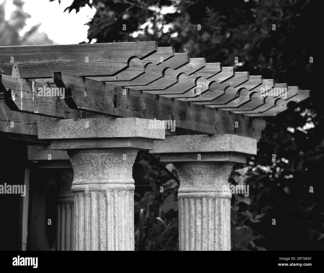 Una scala di grigi di colonne romane sormontate da una struttura a pergola in legno Foto Stock