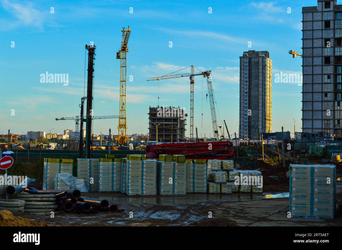 cantiere nel centro della città. i materiali da costruzione sono impilati sotto la pellicola. case costruite in lontananza, gru edili sono state Foto Stock