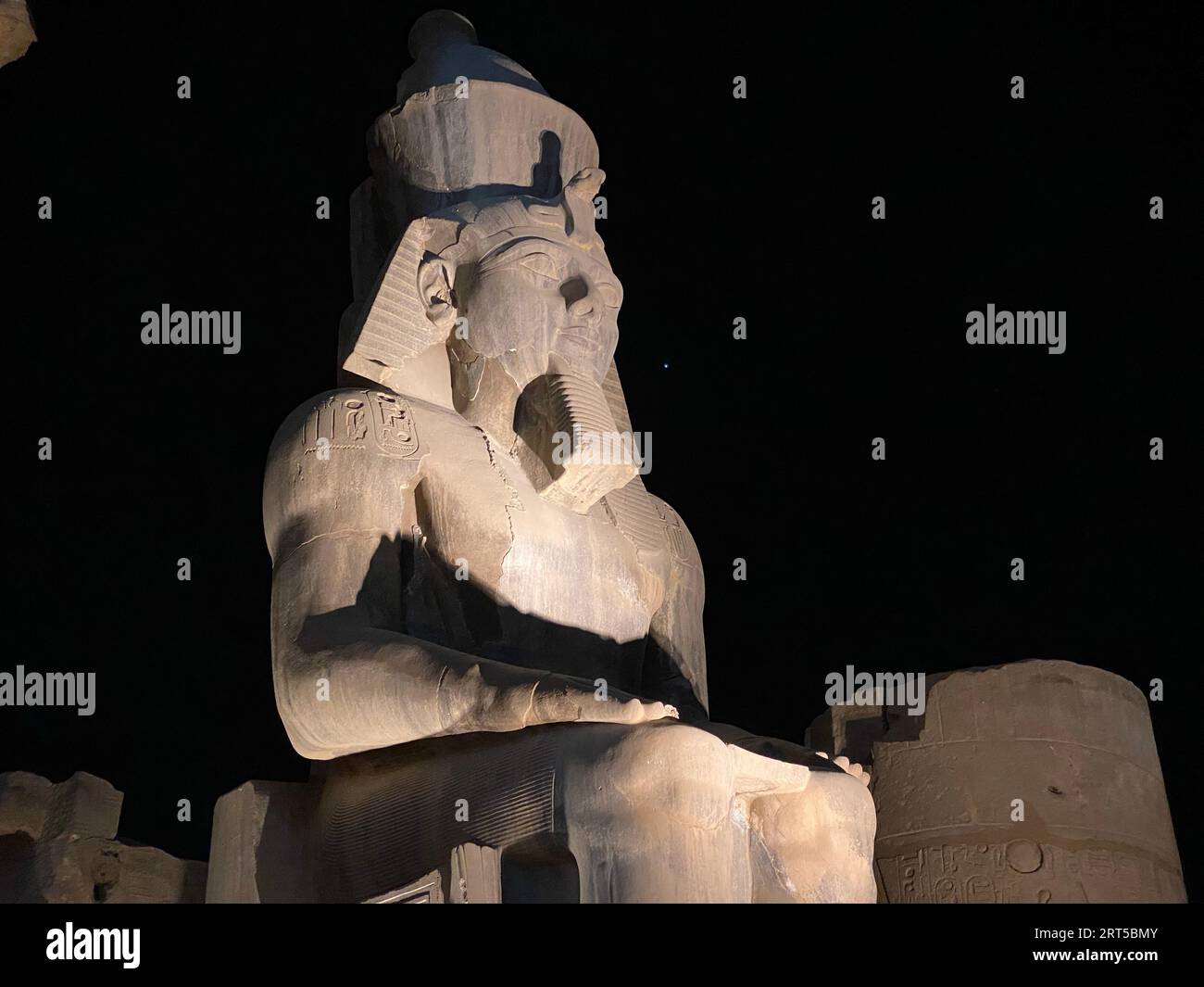 L'antica statua seduta di Ramses II nel Tempio di Luxor illuminata di notte Foto Stock