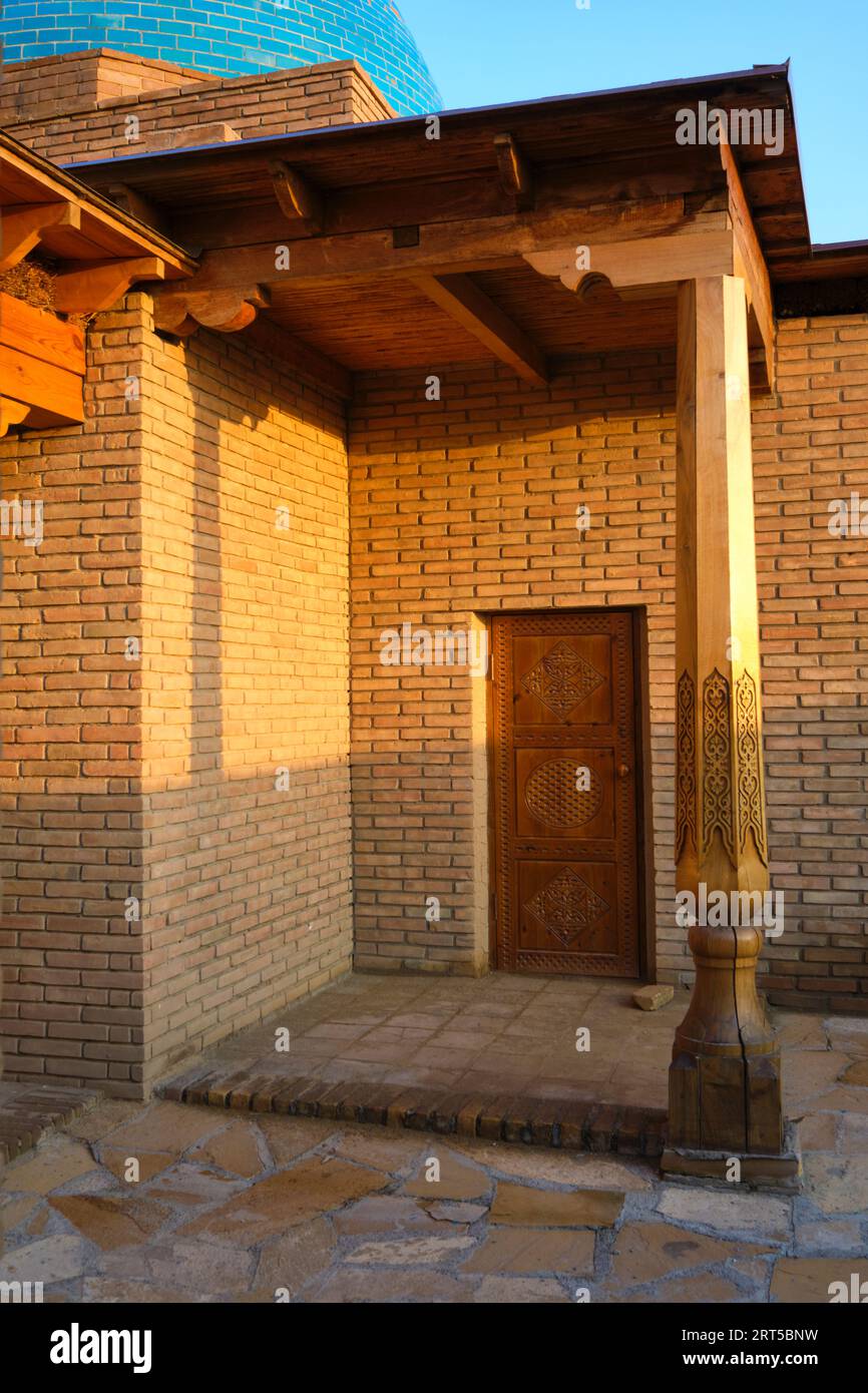 Un lato, una porta sul retro e un portico al tramonto, dorato e luminoso. Alla moschea di Khan in Turkestan, Kazakistan. Foto Stock