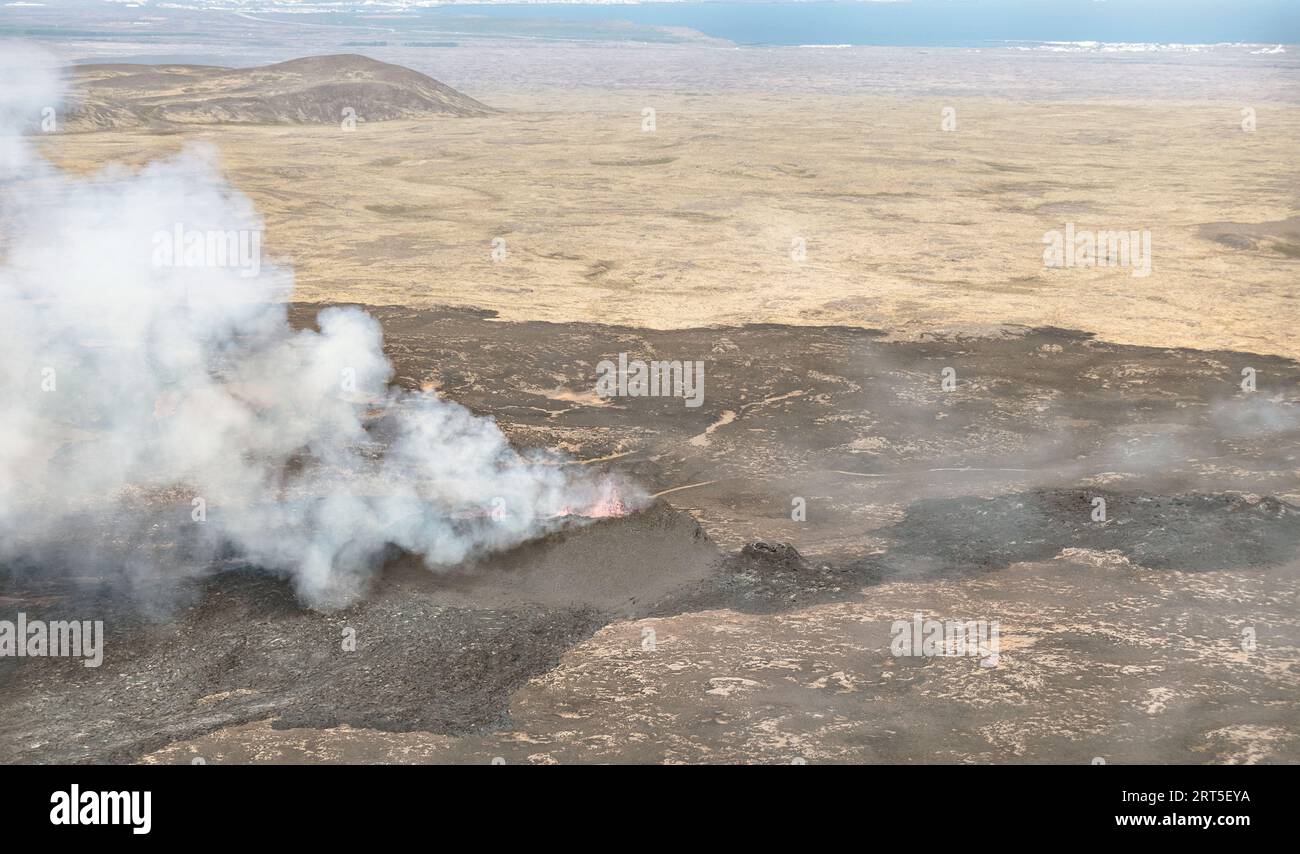 Vista aerea ravvicinata dell'eruzione del vulcano Litli-Hrutur vicino a Reykjavik in Islanda, che mostra le fiamme della lava calda circondate da fumo e foschia Foto Stock