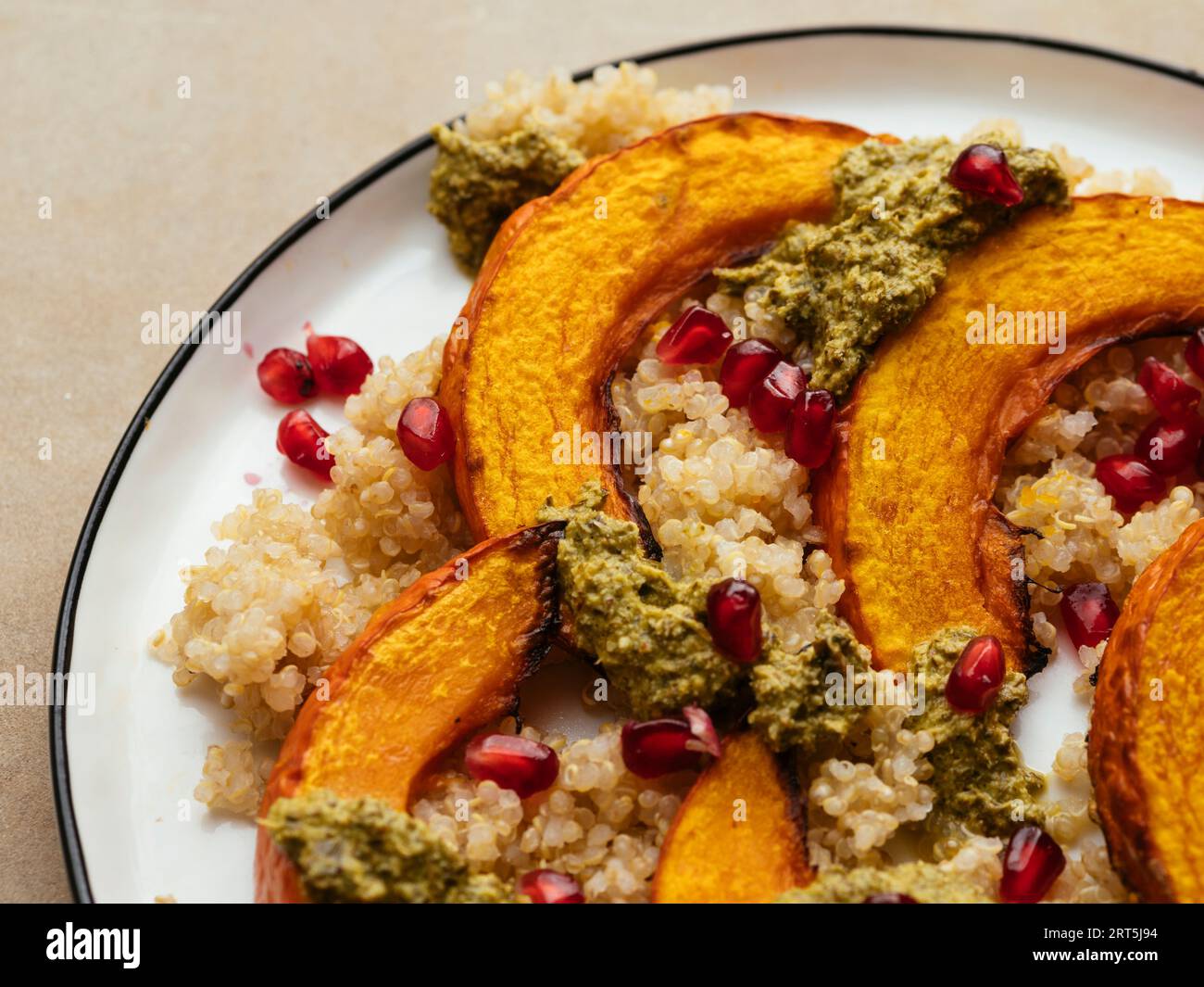Zucca invernale tostata fatta in casa con quinoa e pesto di menta, guarnita con arils di melograno. Foto Stock