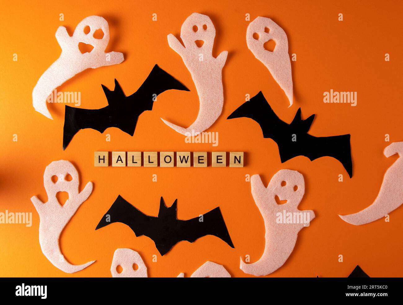 Fantasmi bianchi e mazza per la festa di Halloween. Immagine fantasma della carta di avvolgimento su sfondo arancione vista dall'alto. Fumetto Creepy Whisper. Fai-da-te fatto a mano. Impostare i caratteri boo. Parola frase di legno della lettera. Foto Stock