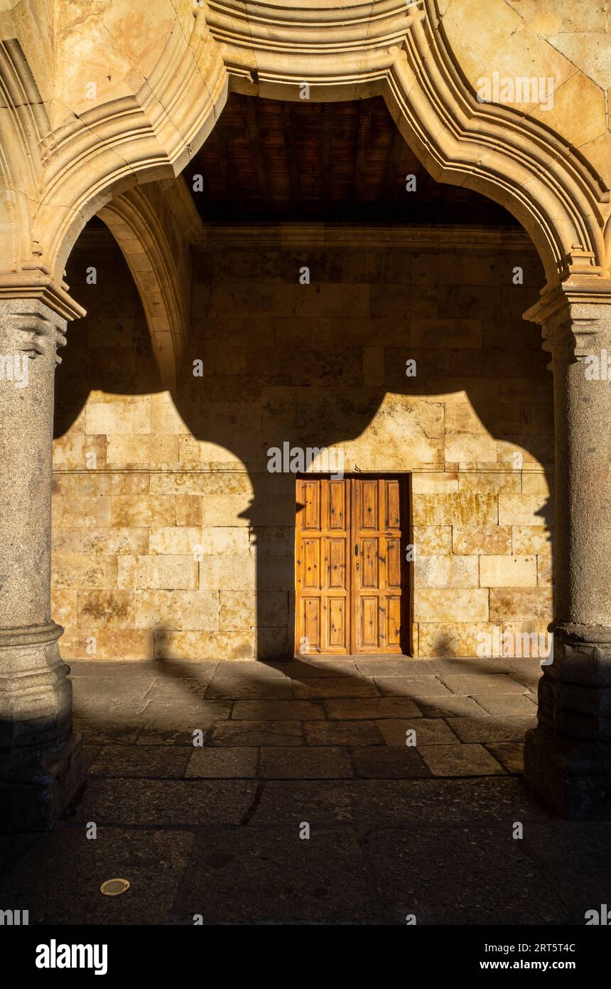 Arco e colonna del chiostro dell'Università di Salamanca con la sua ombra sulla parete del corridoio dalla luce del sole serale che incornicia una o Foto Stock