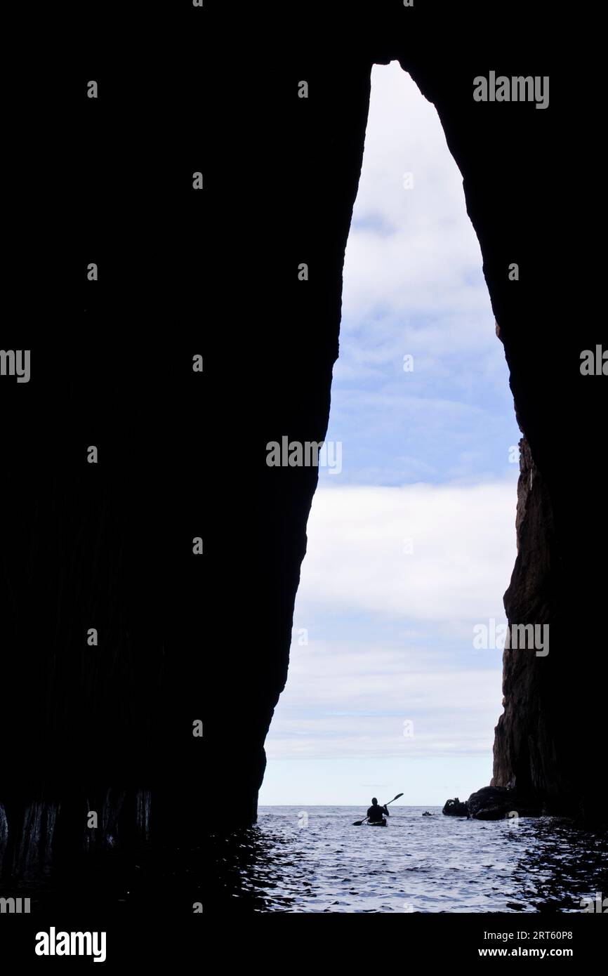 Un kayak marino esplora un'enorme grotta marina sull'isola di Schouten, Freycinet NP, Tasmania, Australia. Foto Stock