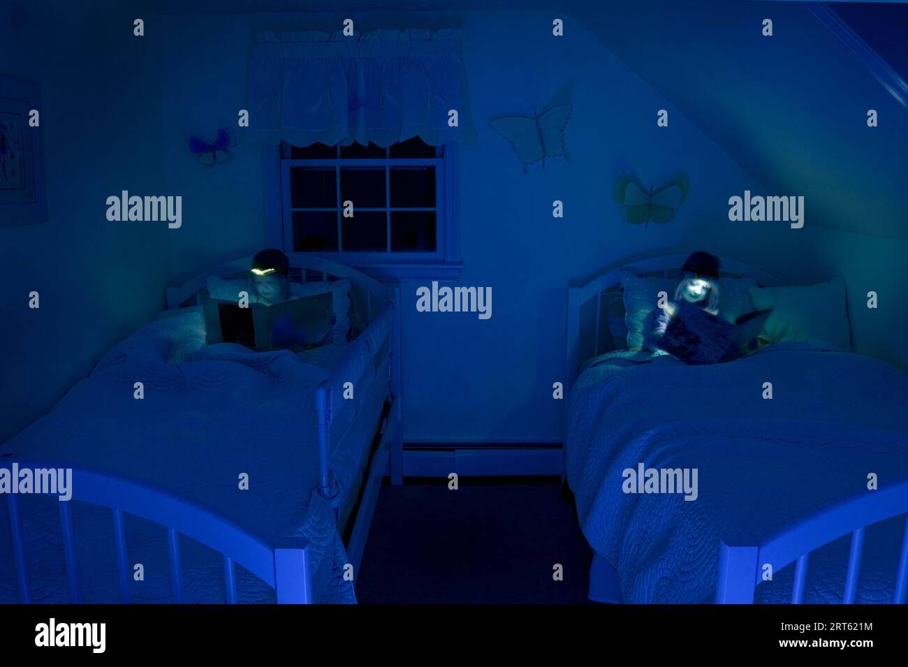 Ragazze che leggono a letto con un faro di notte. Foto Stock