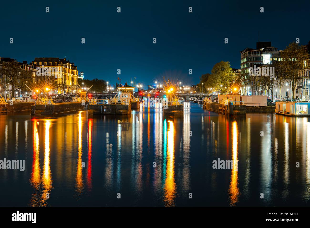 Canali illuminati e delizie sul lungofiume: Esplorare Amsterdam dopo il tramonto Foto Stock
