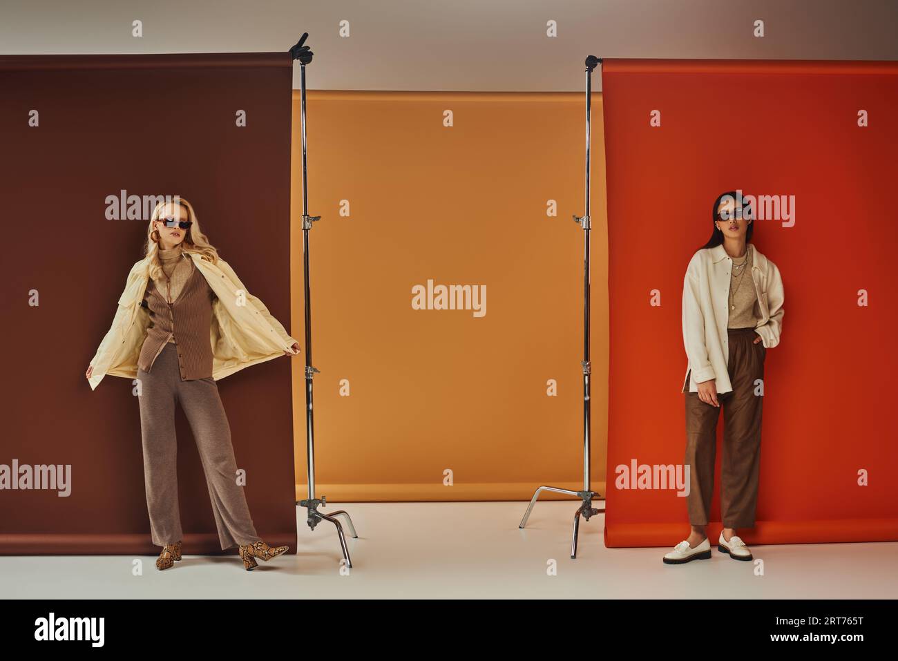 guardaroba autunnale, eleganti modelli multietnici con occhiali da sole e capispalla in uno sfondo colorato Foto Stock