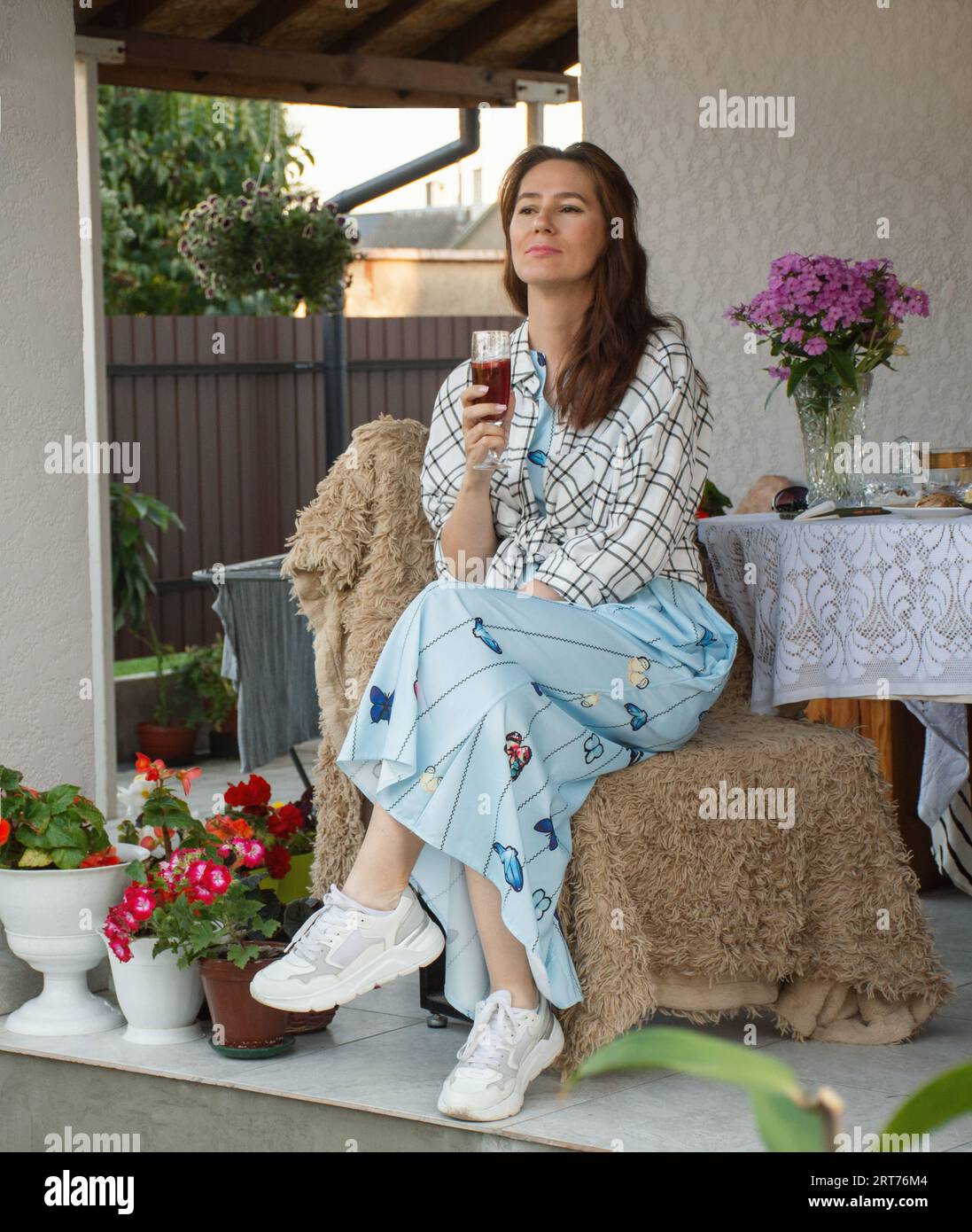 una donna felice che passa la serata con un bicchiere di vino sulla terrazza di casa sua Foto Stock