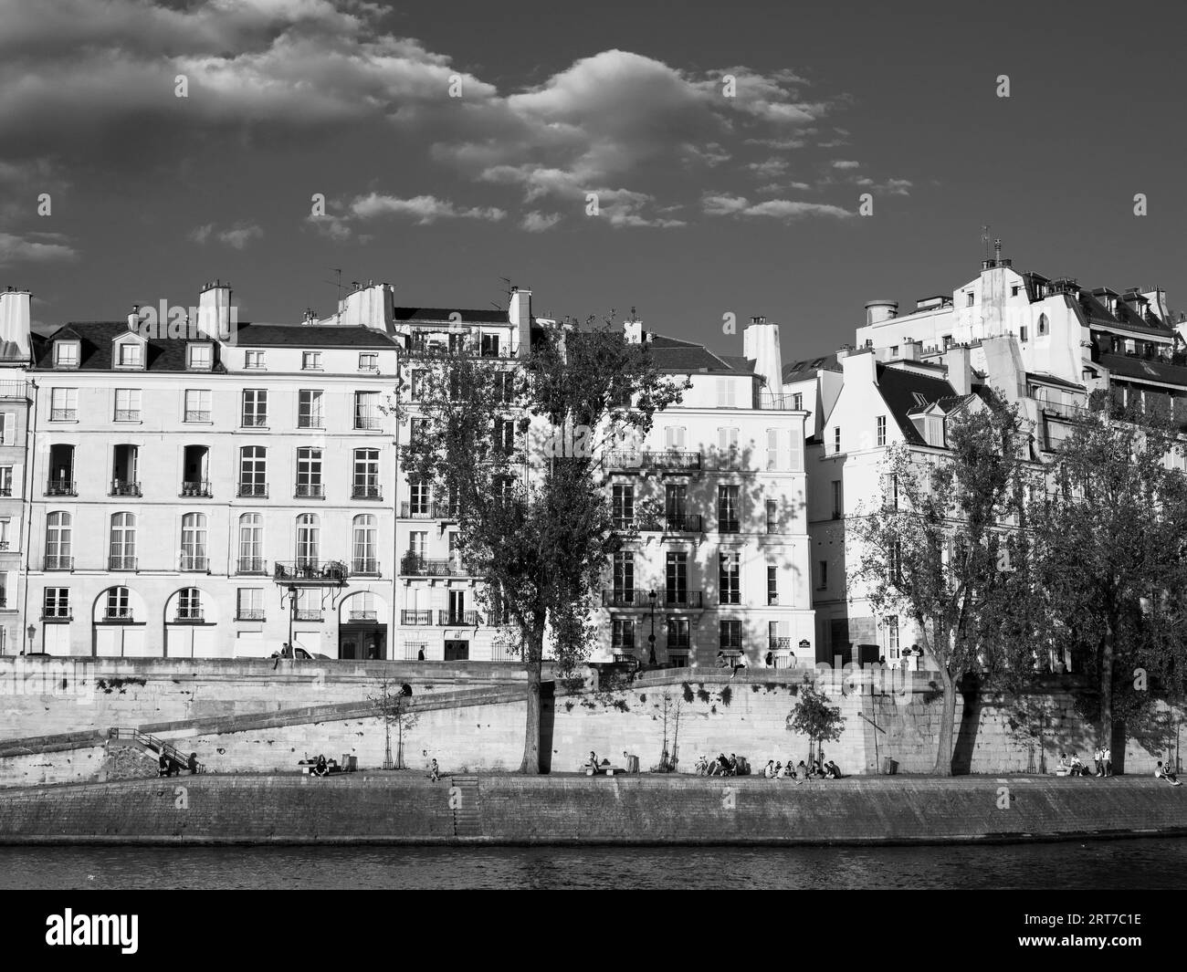 Bianco e nero, luce della sera, appartamenti e persone che si rilassano sulla riva del fiume Senna, Île Saint-Louis, Parigi, Francia, Europa, UE. Foto Stock