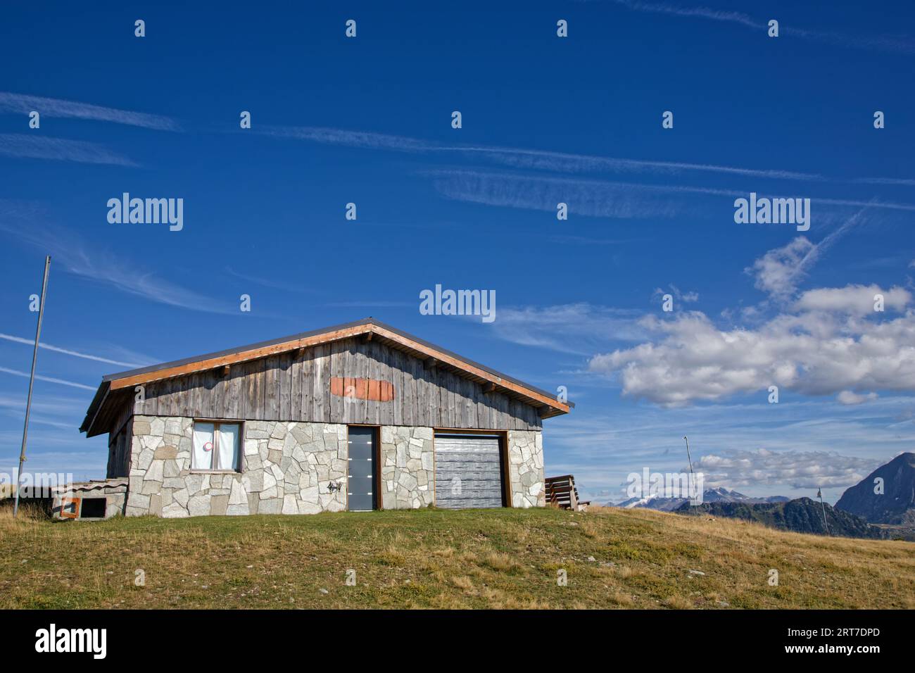 Un rifugio in pietra sulle pendici di Belledonne con paesaggi innevati sulle montagne dietro Foto Stock
