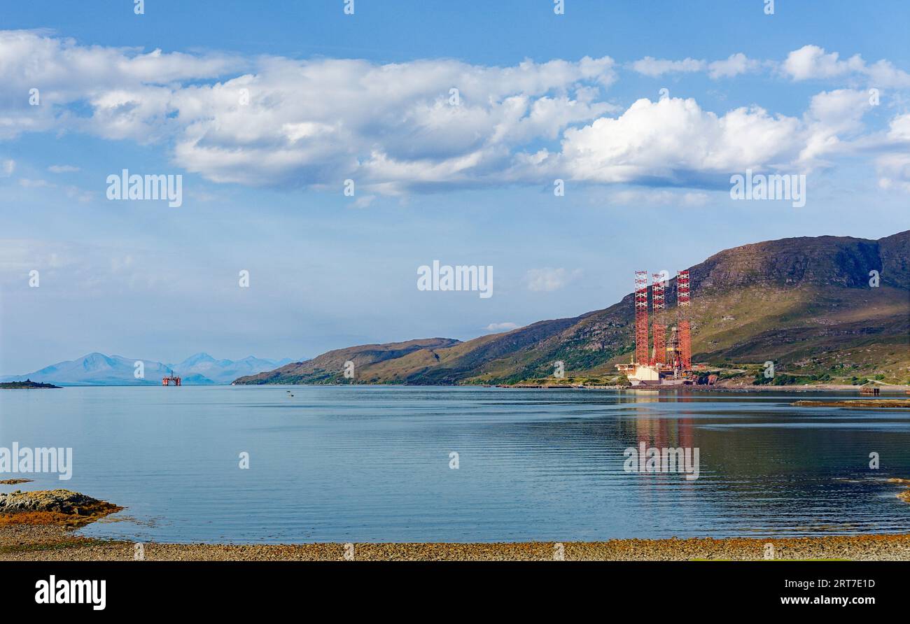 Porto di Kishorn e bacino di carenaggio della Scozia, vista sul lago, su una costruzione di una piattaforma di perforazione e su una piattaforma di produzione di olio d'arancio in lontananza Foto Stock
