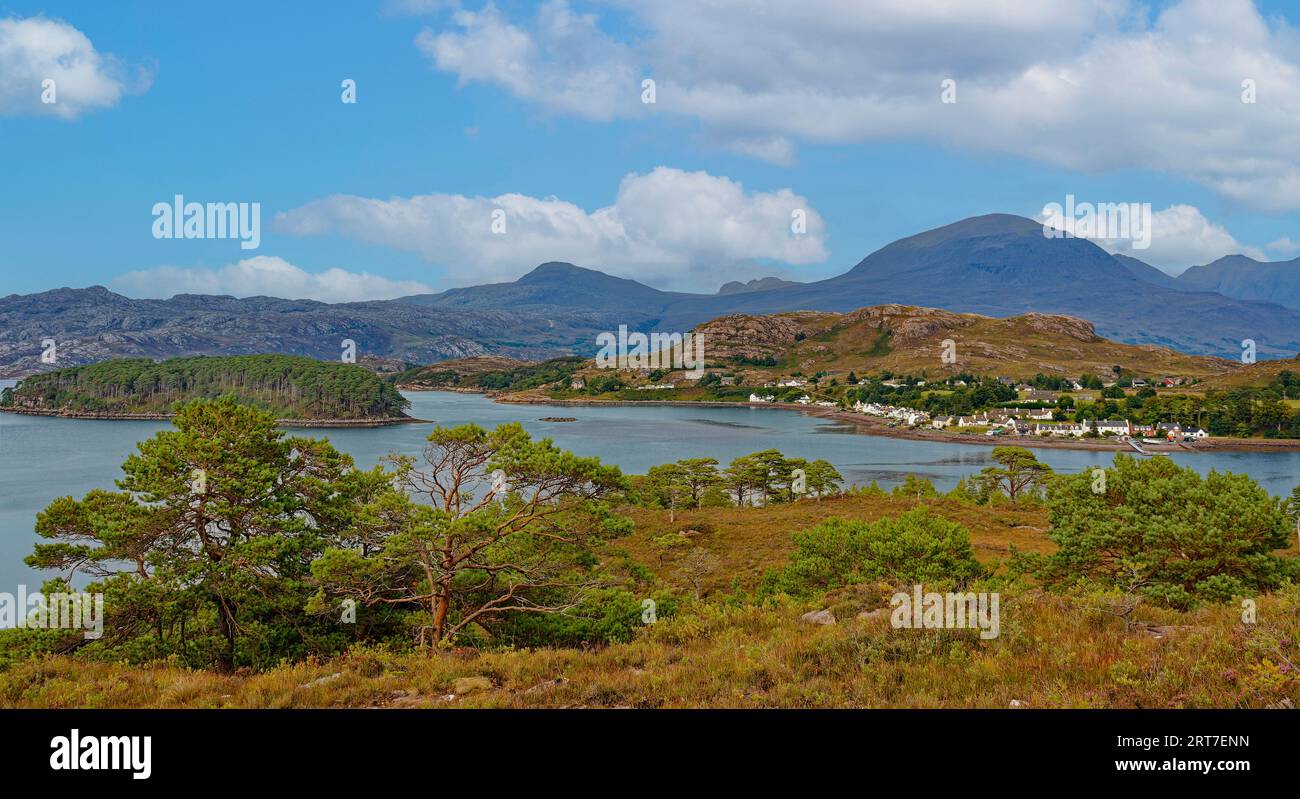 Shieldaig Sutherland Scozia vista attraverso gli alberi e Loch fino alle case del villaggio e alle colline in tarda estate Foto Stock