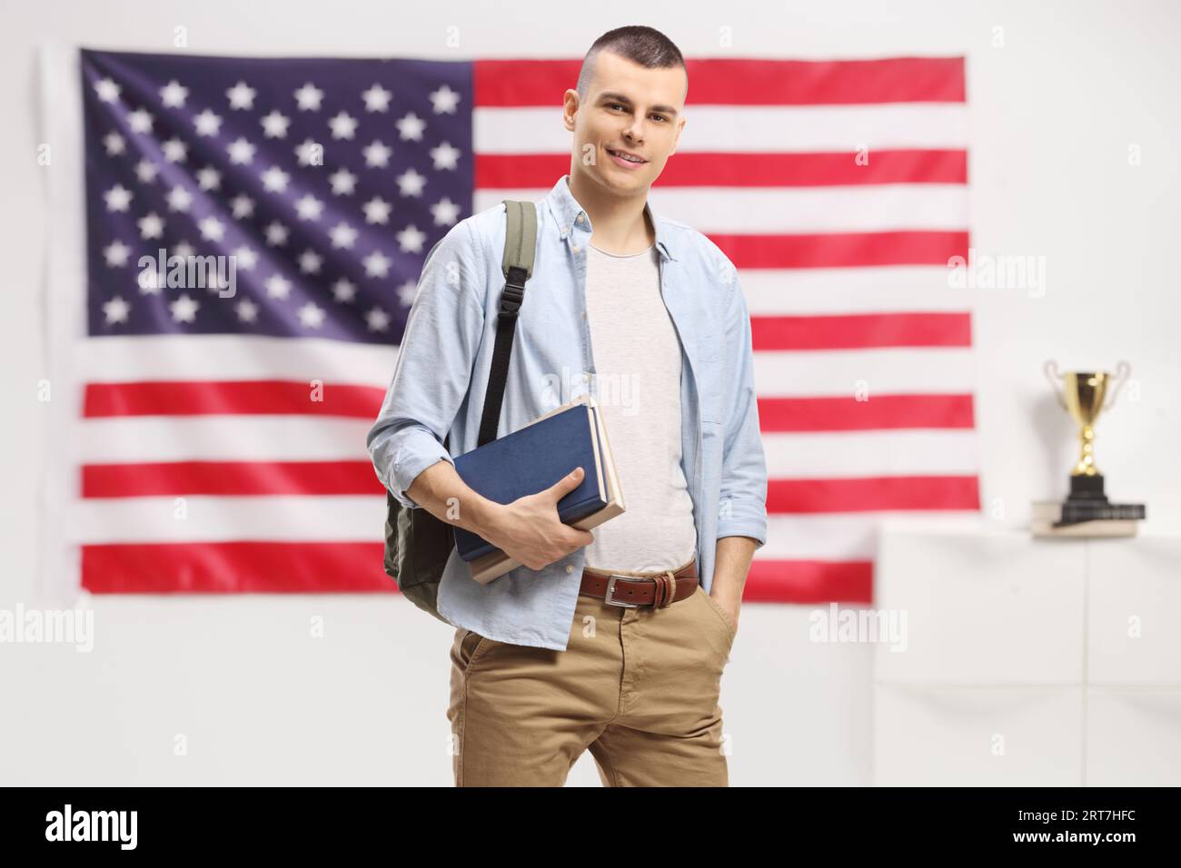 Studente maschio con zaino e libri con una bandiera USA sullo sfondo Foto Stock