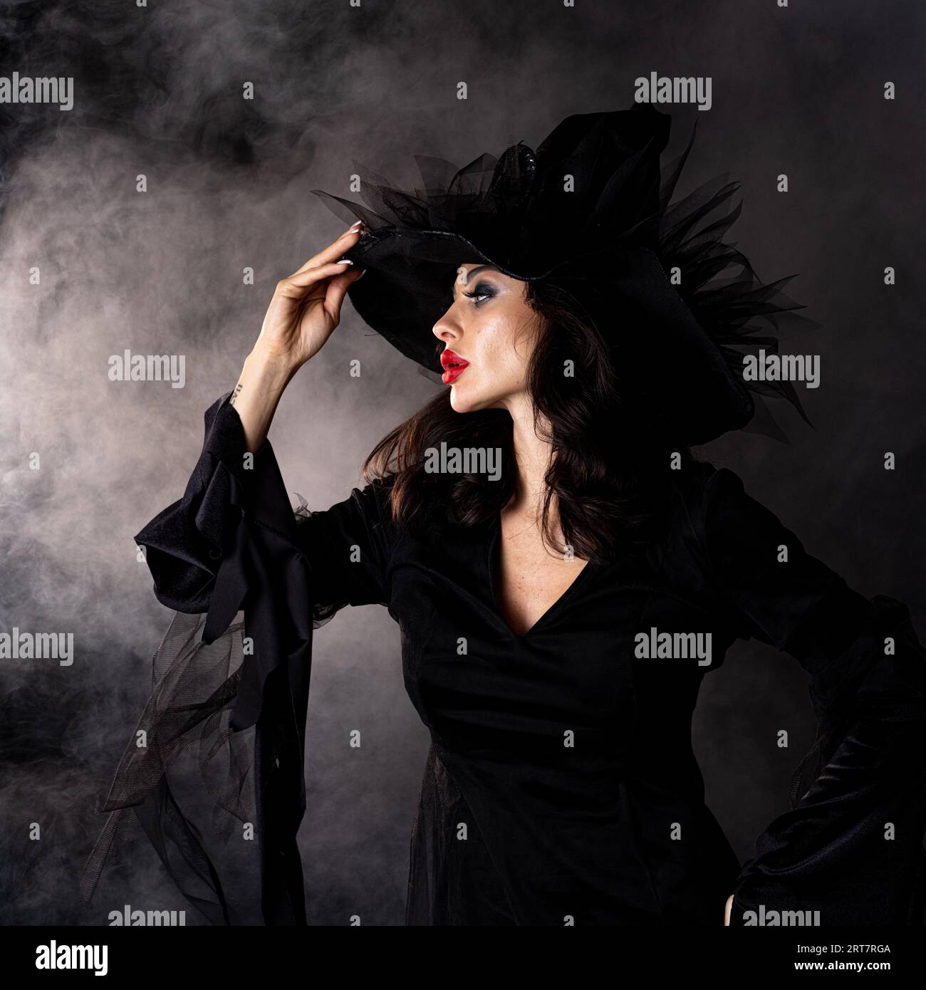 Sexy giovane strega bruna con mettere un incantesimo in nebbia Halloween costume partito Foto Stock
