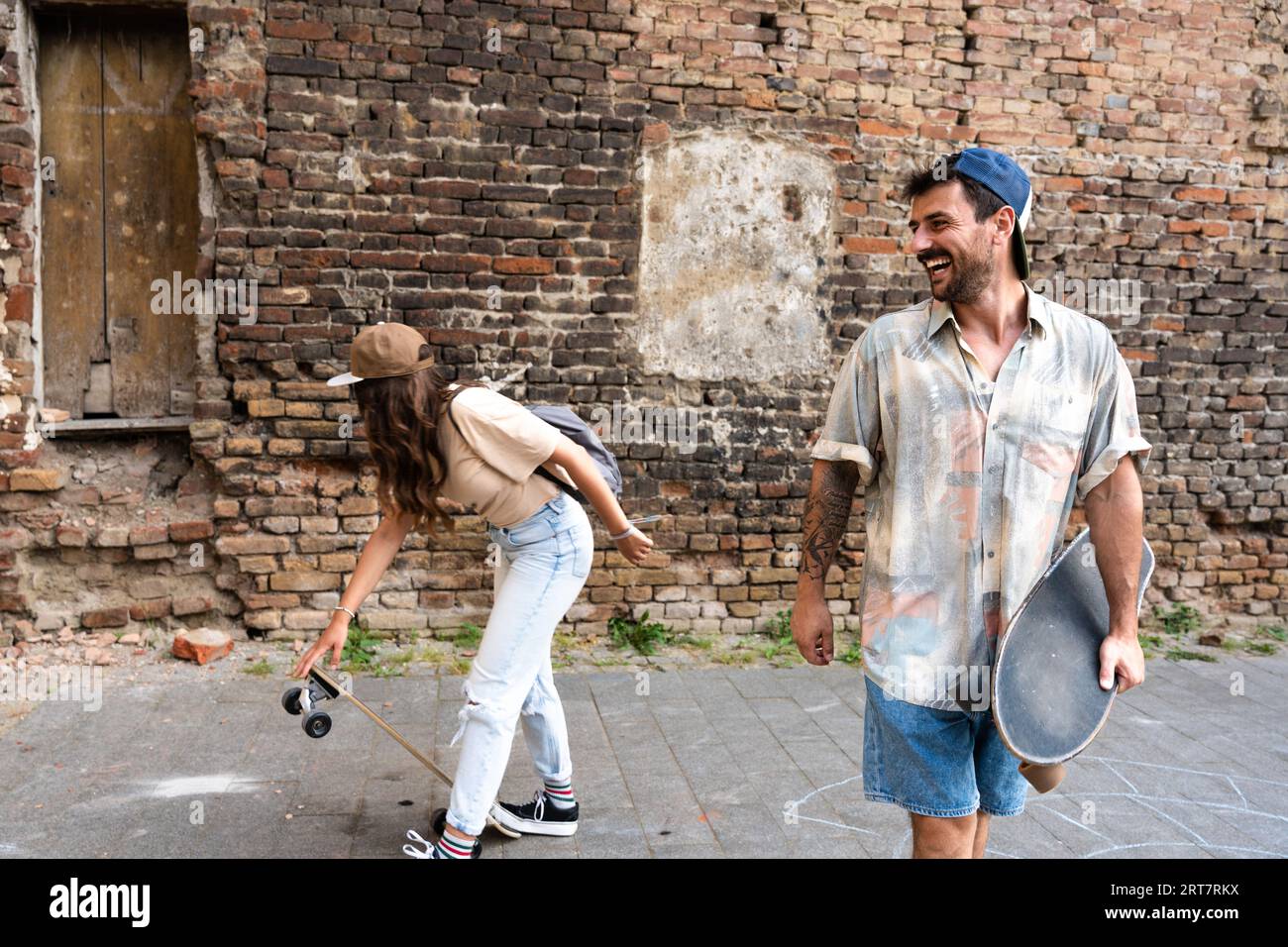 Ritratto di giovani coppie con skateboard e longboard che si divertono all'aperto. Uomo e donna, fidanzato e fidanzata pattinatori che si divertono a pattinare nel tempo libero Foto Stock