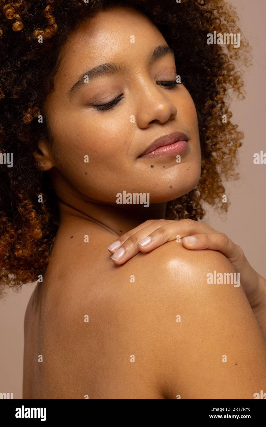 Donna birazziale con capelli ricci scuri sorridente con gli occhi chiusi e la mano sulla spalla Foto Stock