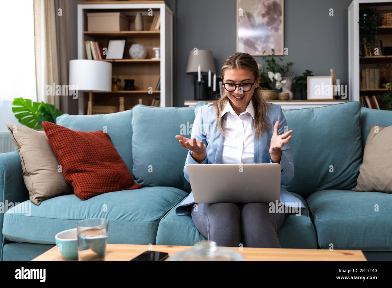 Una giovane donna d'affari effettua una videochiamata dall'ufficio domestico con i dipendenti della sua azienda dà loro un discorso motivazionale e consiglia loro come farlo Foto Stock