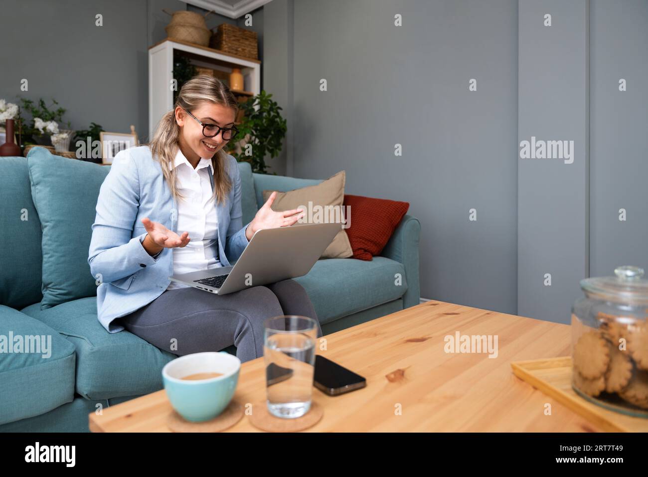 Una giovane donna d'affari effettua una videochiamata dall'ufficio domestico con i dipendenti della sua azienda dà loro un discorso motivazionale e consiglia loro come farlo Foto Stock