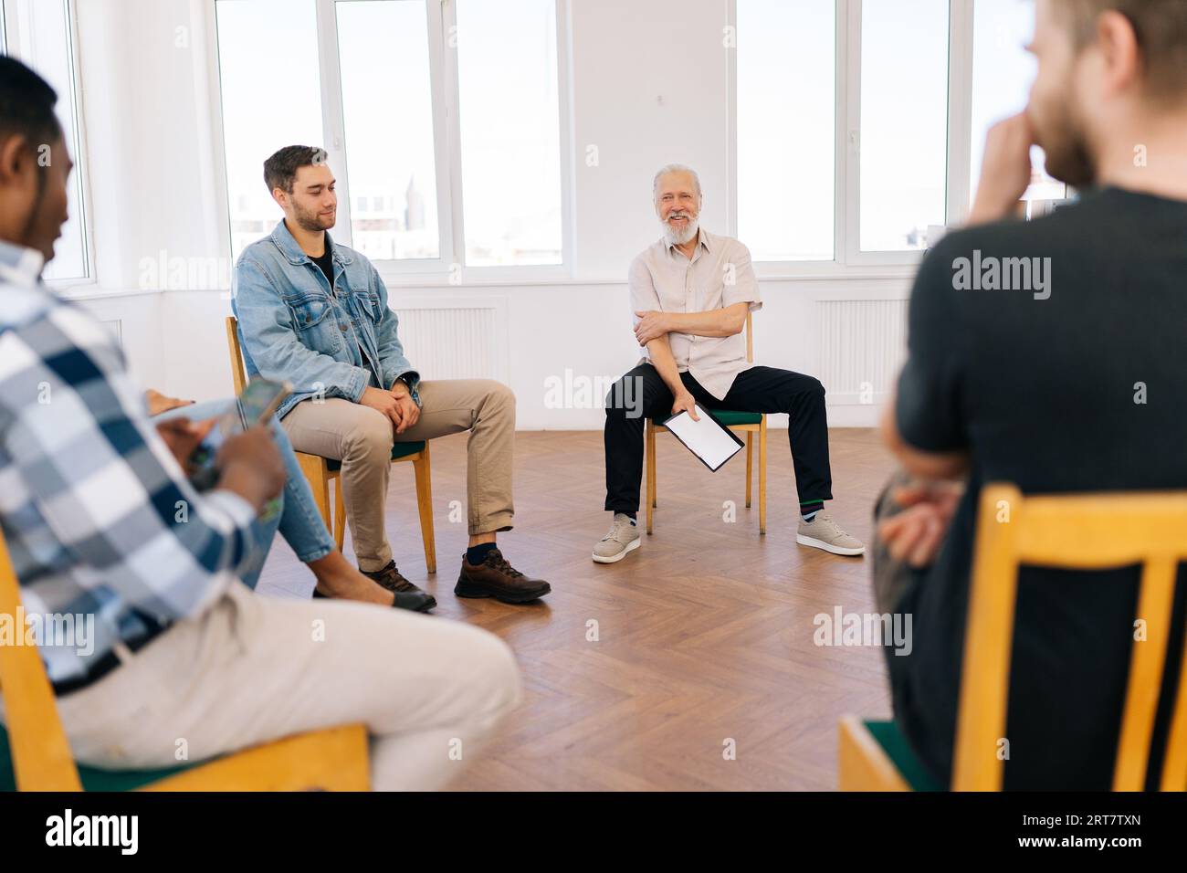 Ritratto di un mentore uomo amichevole e maturo, leader aziendale che comunica con un team professionale multirazziale, gruppo di personale di stagisti Foto Stock