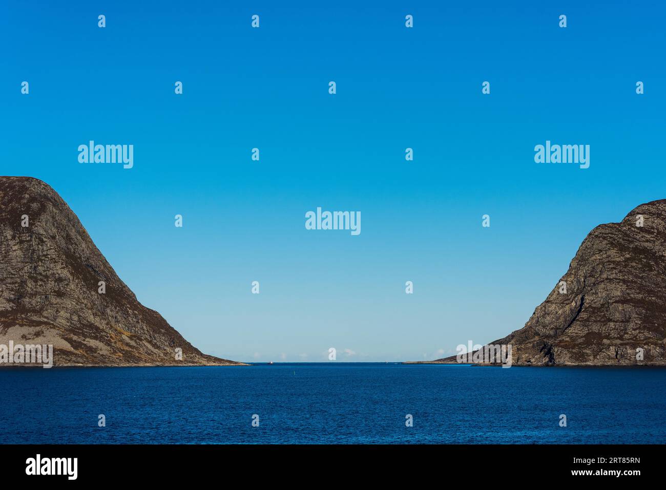 Montagne a forma di U che fieggiano un fiordo sulla costa della Norvegia in giornata di sole con cielo blu Foto Stock