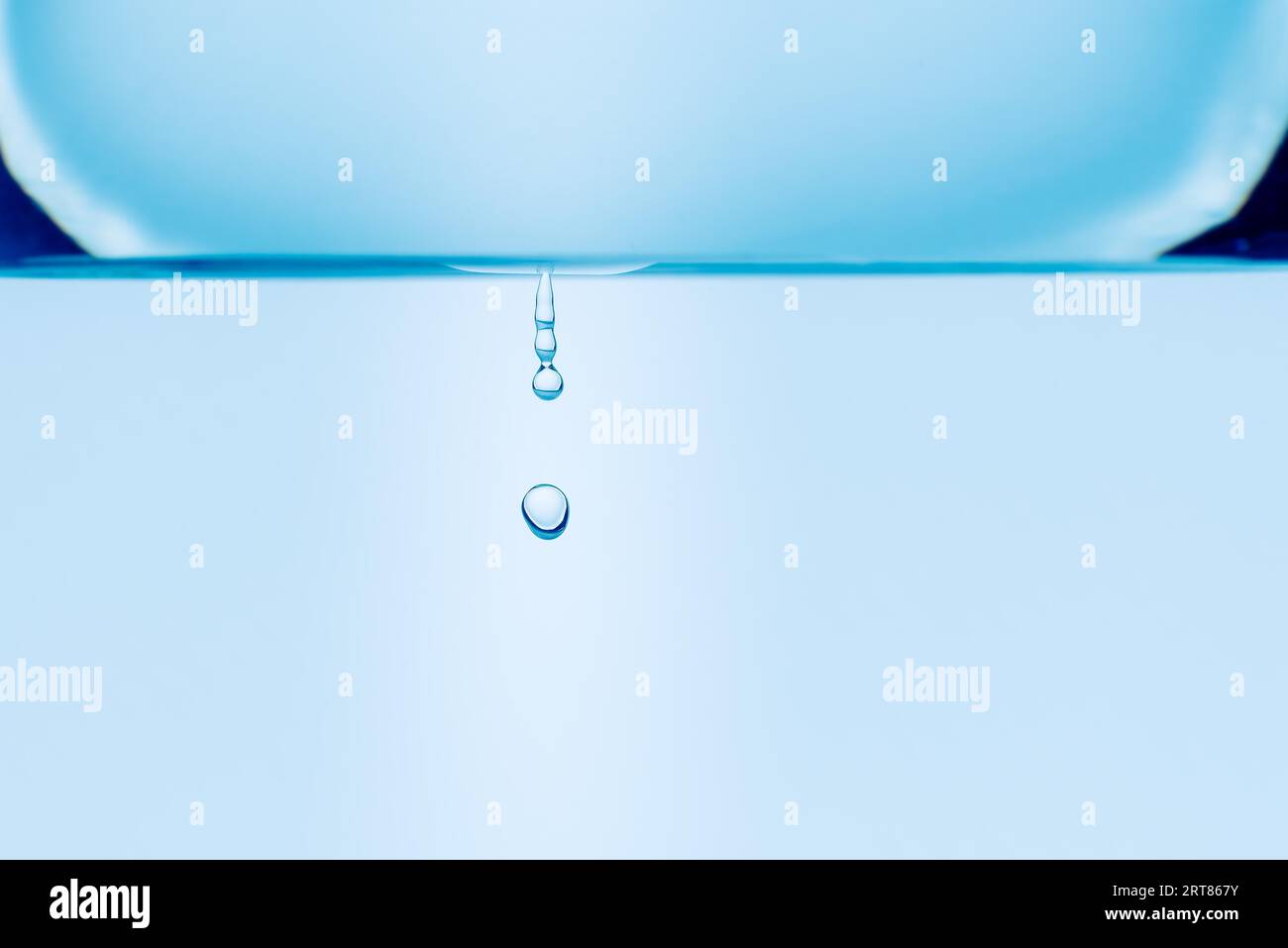 Dettaglio capovolto delle gocce d'acqua che cadono dal vetro di acqua nello spazio libero isolato su sfondo bianco Foto Stock