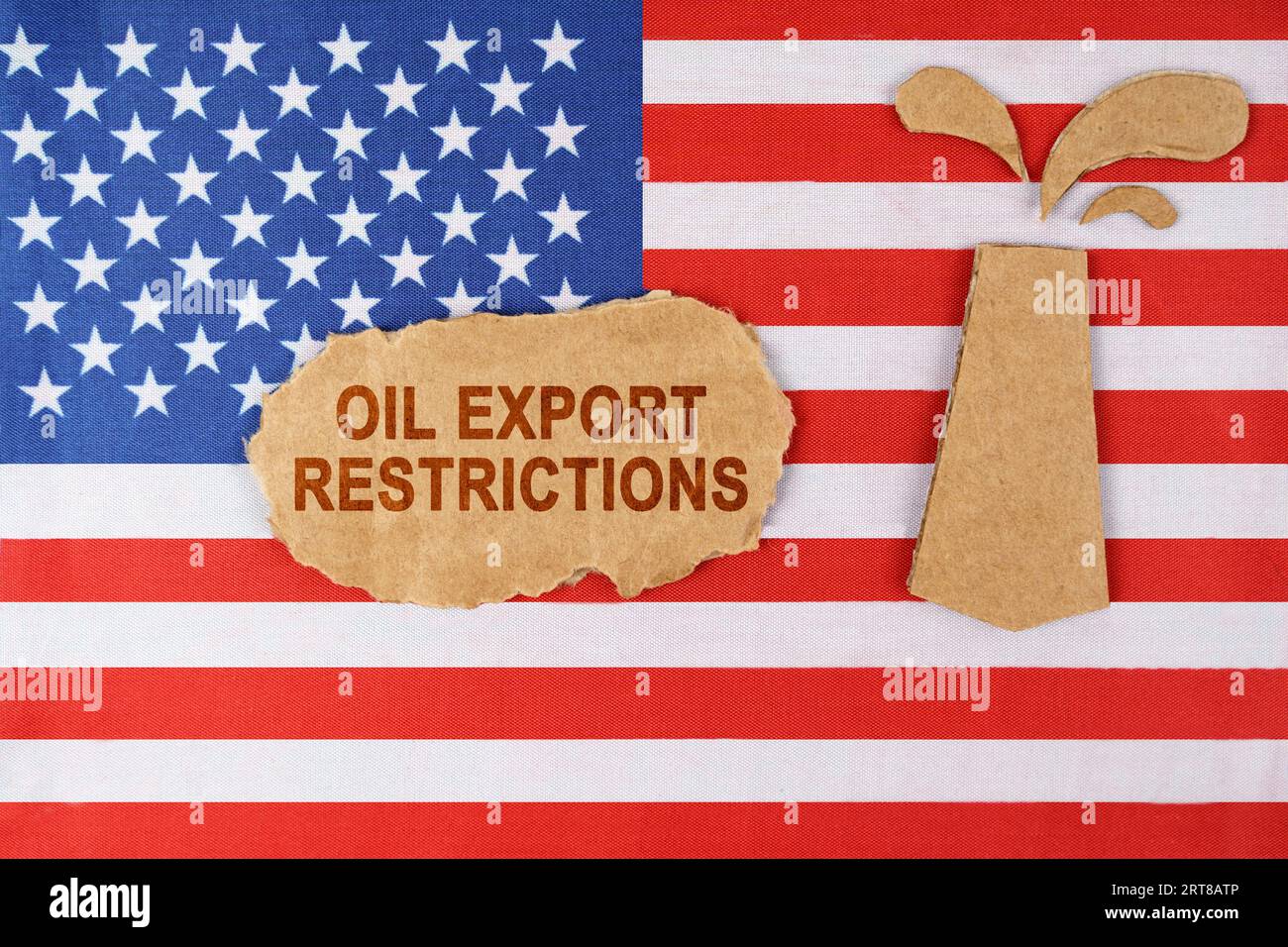 Sulla bandiera degli Stati Uniti c'è una piattaforma petrolifera tagliata fuori dal cartone e un cartello con la scritta "restrizioni all'esportazione di petrolio". Foto Stock