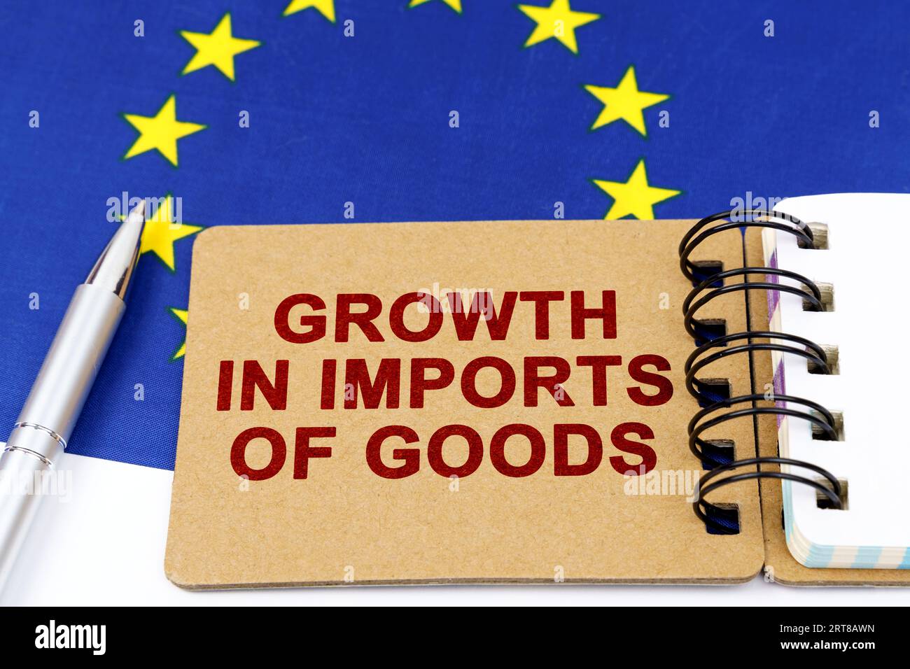 Economia e finanza. Sulla bandiera dell'Unione europea si trovano una penna e un blocco note con l'iscrizione: Crescita delle importazioni di beni. Foto Stock