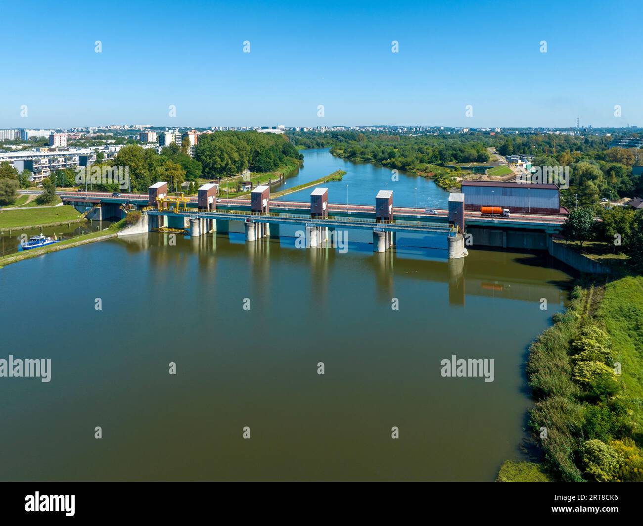 Cracovia, Poalnd. Diga di Dabie sul fiume Vistola con ponte e piccola centrale idroelettrica sulla destra e serranda d'acqua con barca sulla sinistra Foto Stock