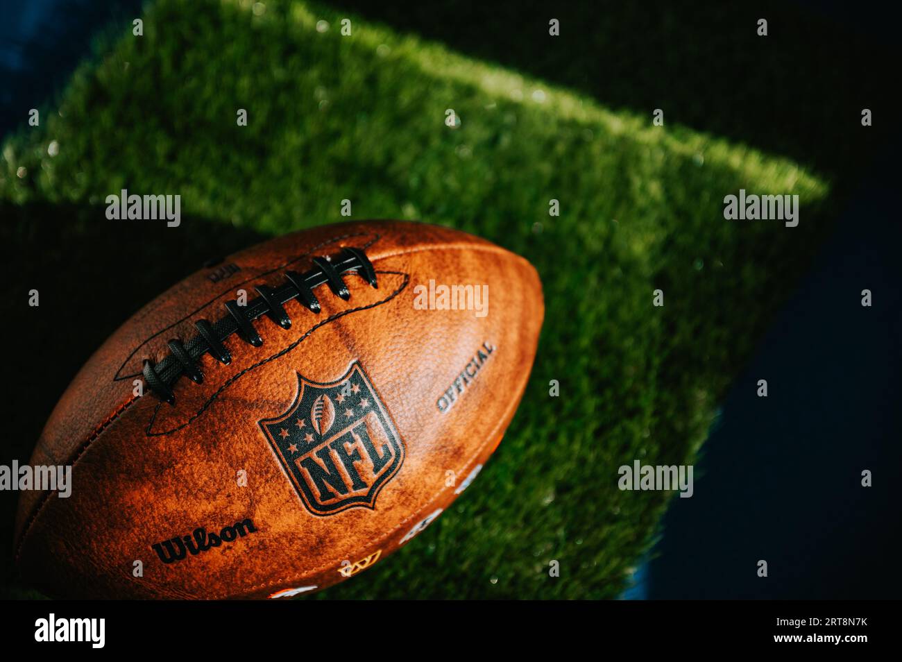 NEW YORK, USA, 11 SETTEMBRE 2023: Marchio NFL: Palla in pelle e logo iconico. Erba verde sullo sfondo, spazio di montaggio nero, leagu del calcio nazionale Foto Stock