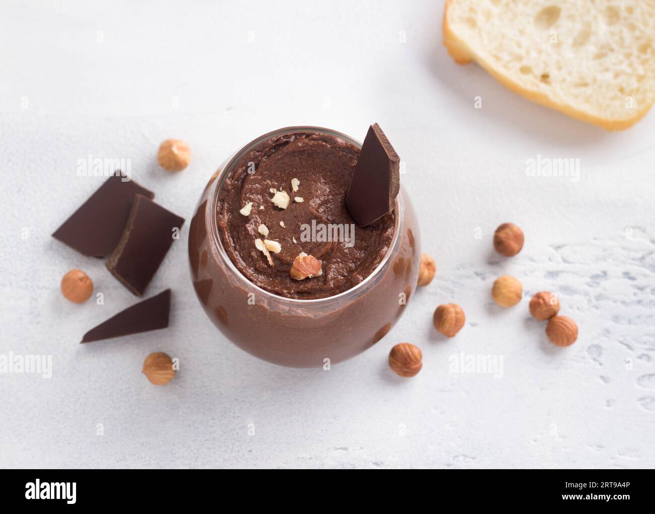 Pasta di cioccolato vegana con banana e noci circondata da ingredienti: Cioccolato e nocciole su sfondo grigio chiaro, vista dall'alto Foto Stock