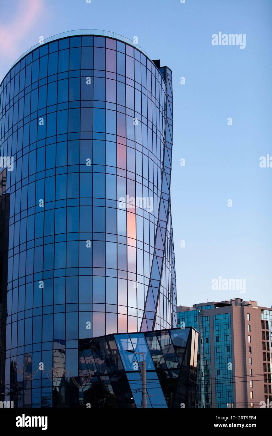 Un alto edificio di vetro accanto ad un classico edificio residenziale. L'urbanismo e il cambiamento tecnologico. Foto Stock