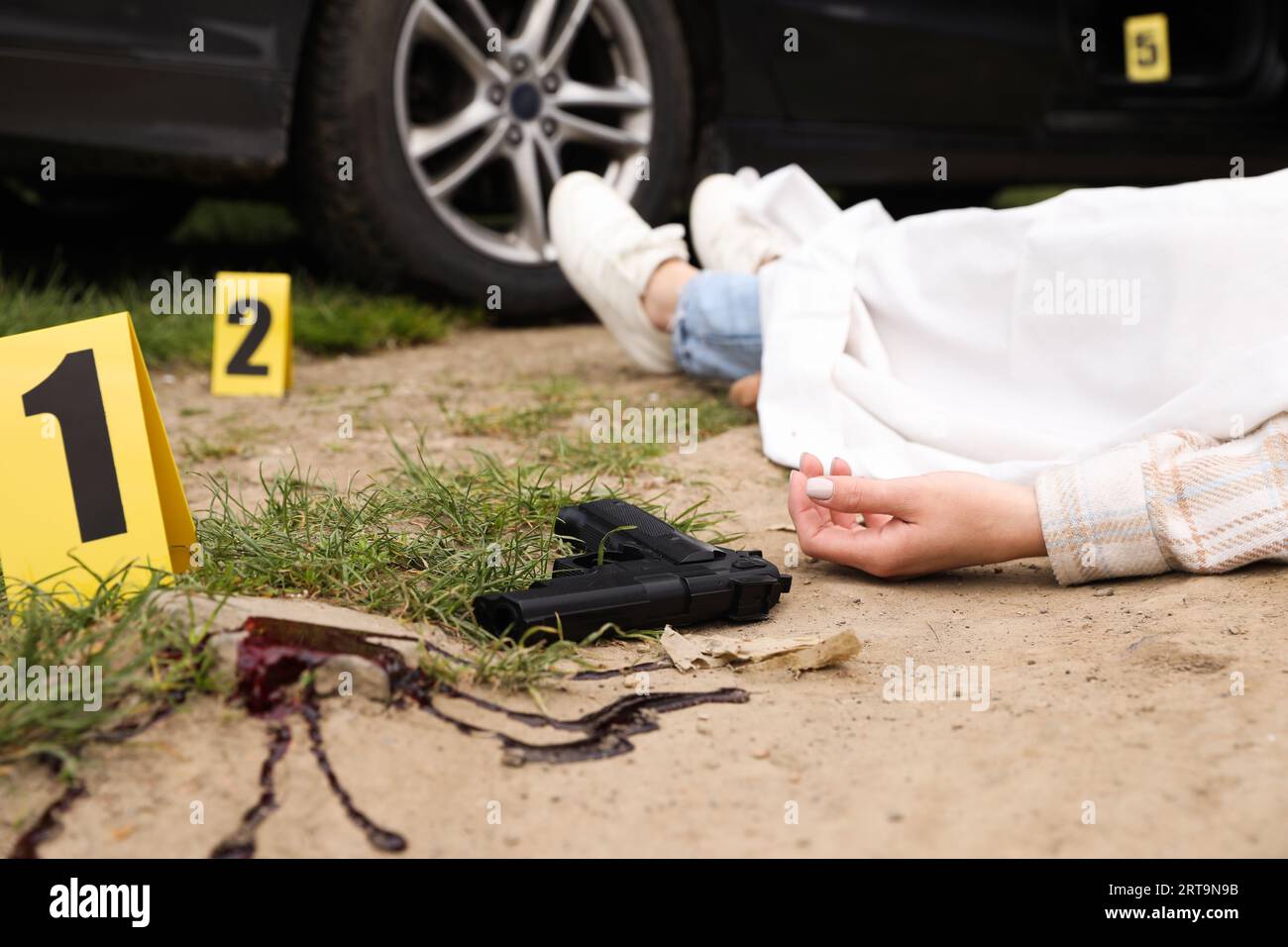 Marcatori della scena del crimine, corpo e pistola di una donna morta all'aperto, primo piano Foto Stock