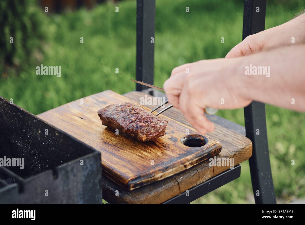Un uomo irriconoscibile prende succosa bistecca da club alla griglia Foto Stock