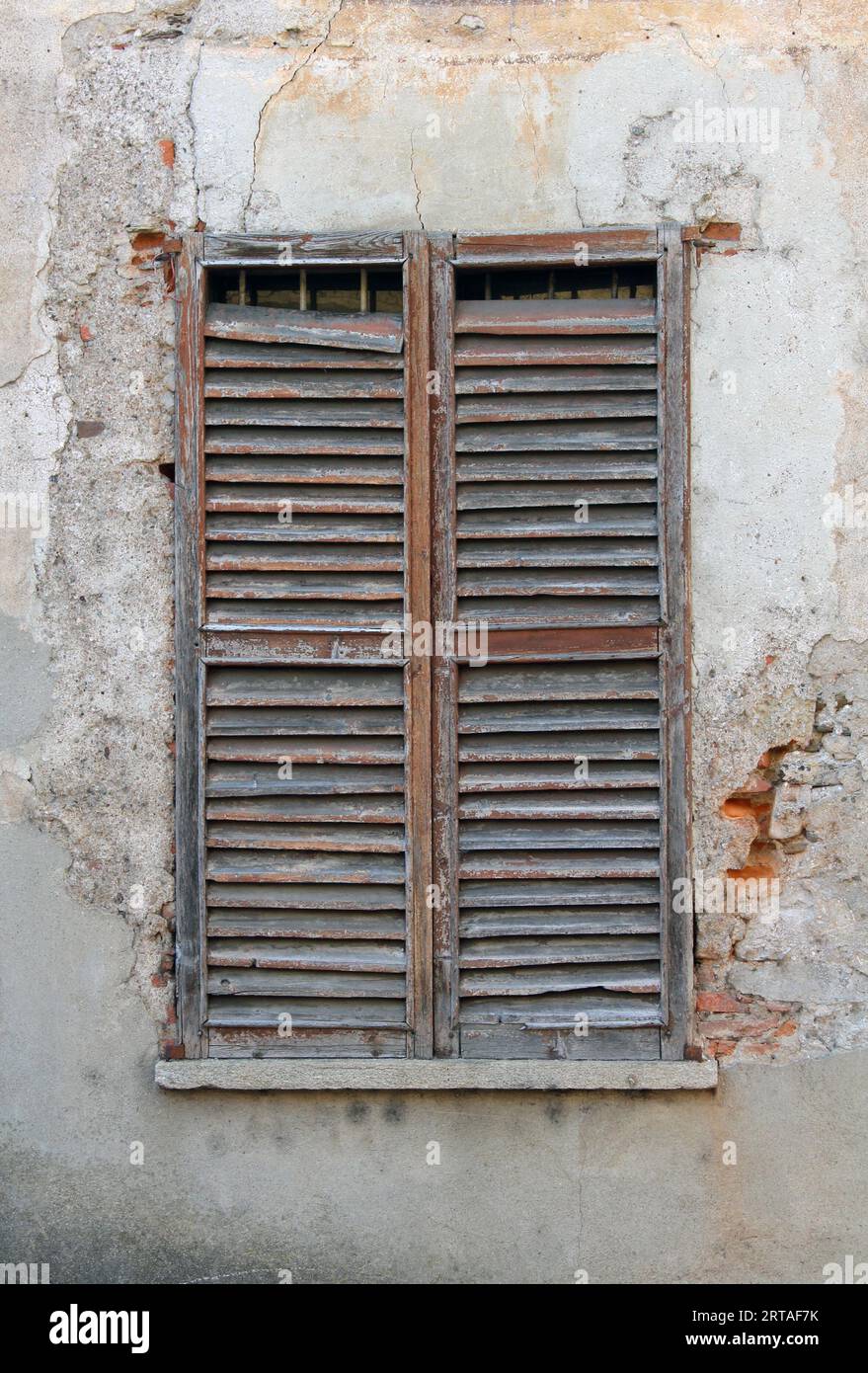 vecchia finestra con persiane, un'antica facciata murale con finestre in legno leggermente rotte perfette come texture di sfondo Foto Stock