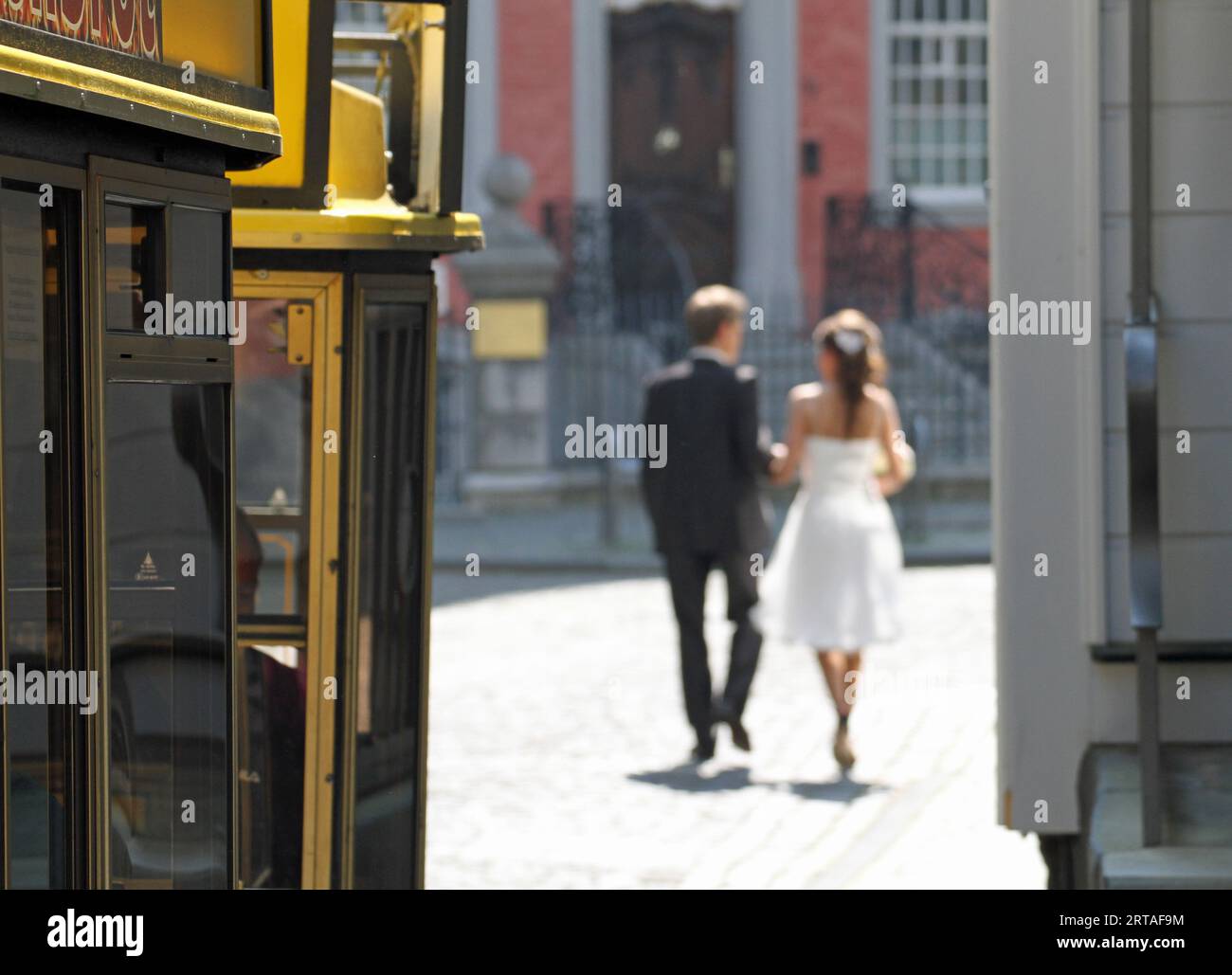 Una giovane e felice coppia sposata subito dopo il matrimonio che se ne va insieme sullo sfondo, gente che cammina per strada Foto Stock