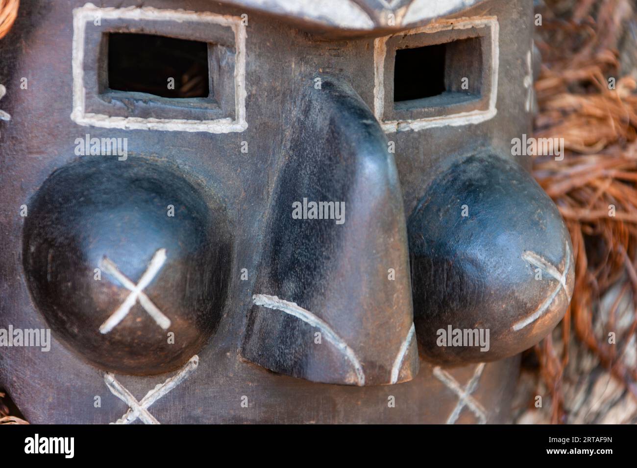 primo piano della tradizionale maschera africana d'epoca in legno con occhi quadrati e naso grande Foto Stock